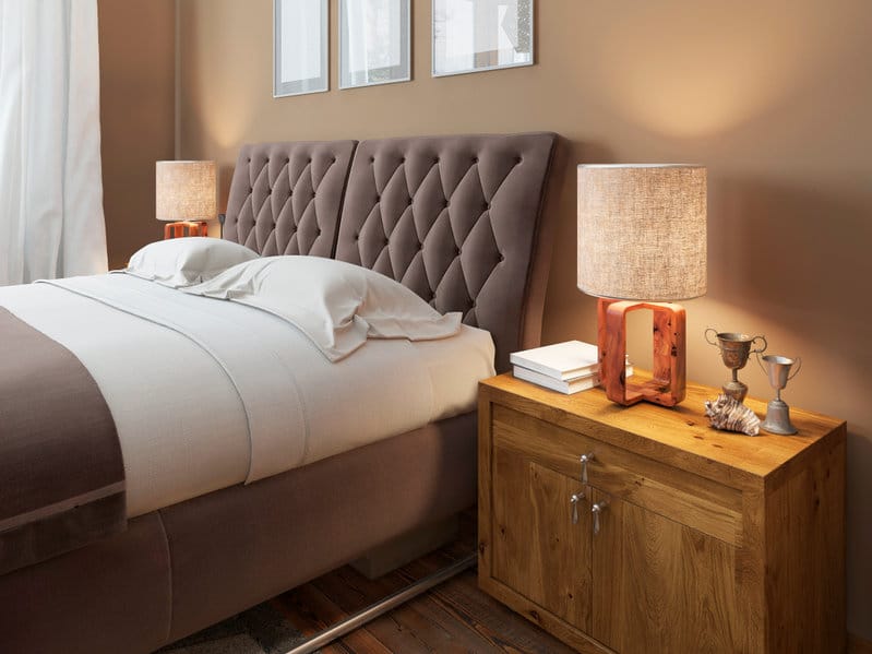 Tables de chevet en bois aux textures expressives dans une chambre moderne. Sur la table de chevet, des lampes au style rustique. Tête de lit matelassée marron. La chambre mansardée. Rendu 3D.